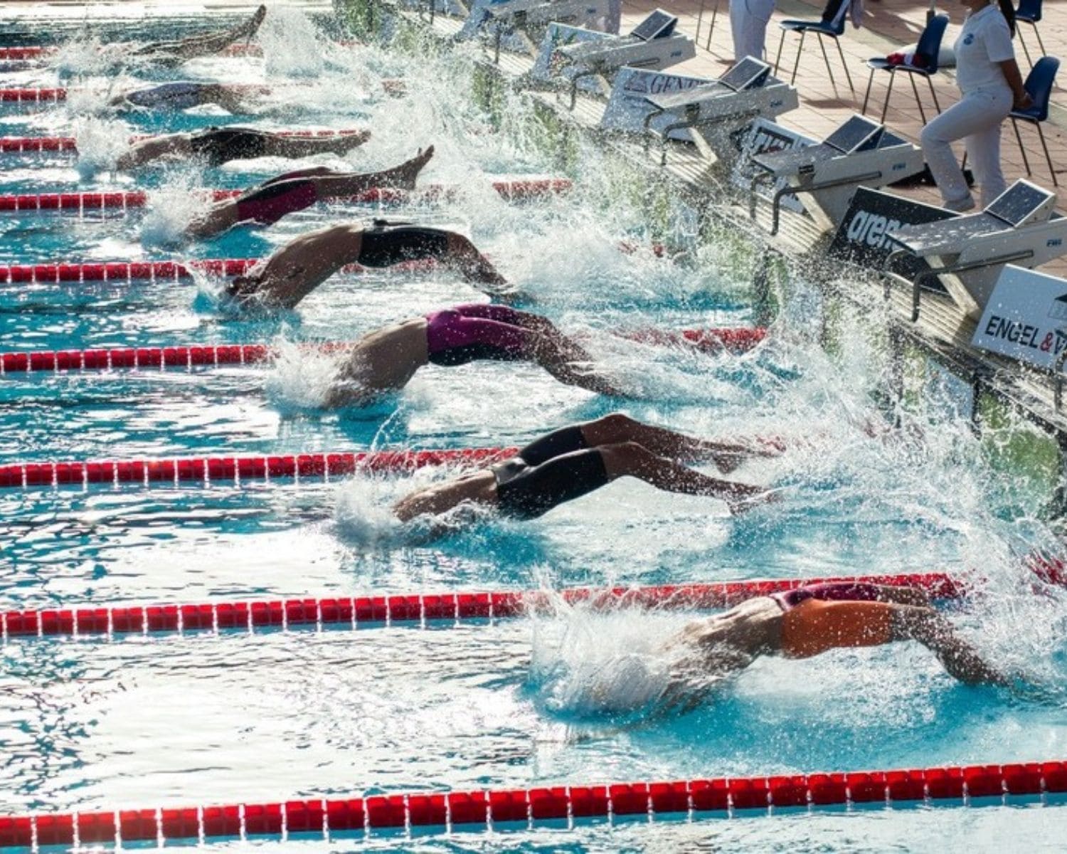 Nadadores realizando una salida de espalda en competición representando la potencia y la intensidad asociadas a la natación competitiva