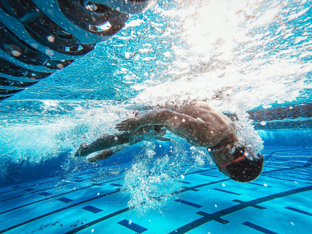 viraje-natacion-entrenamiento-piscina Nadador realizando un viraje de crol en entrenamiento en piscina interior, con enfoque en la técnica y la eficiencia del movimiento bajo el agua